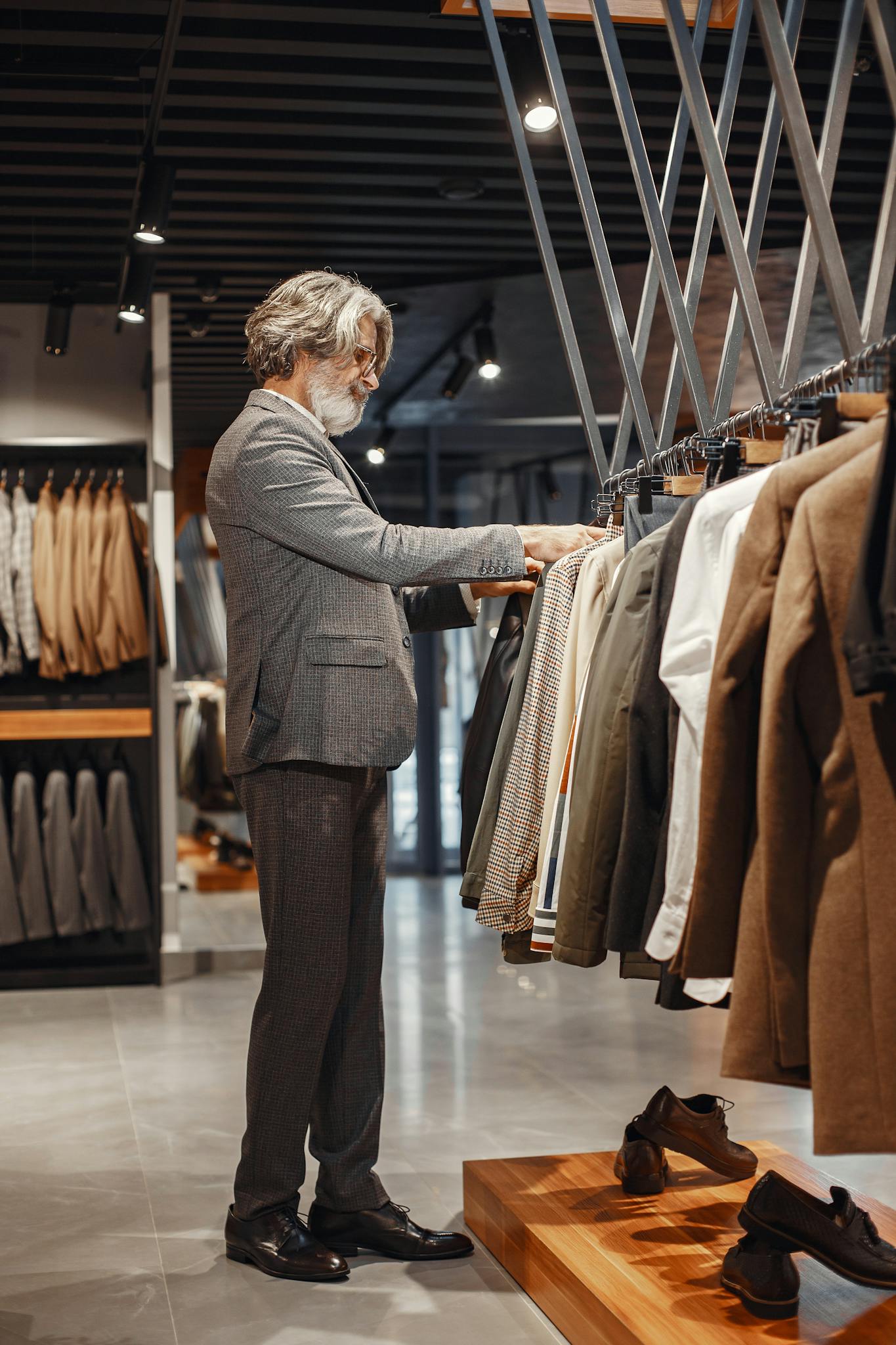 A man browsing clothes in a modern boutique store with a variety of suits on display.