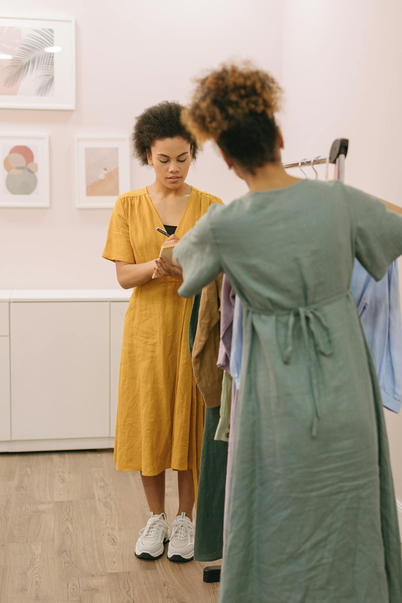 Two women engaged in selecting and noting down outfits in a boutique setting.