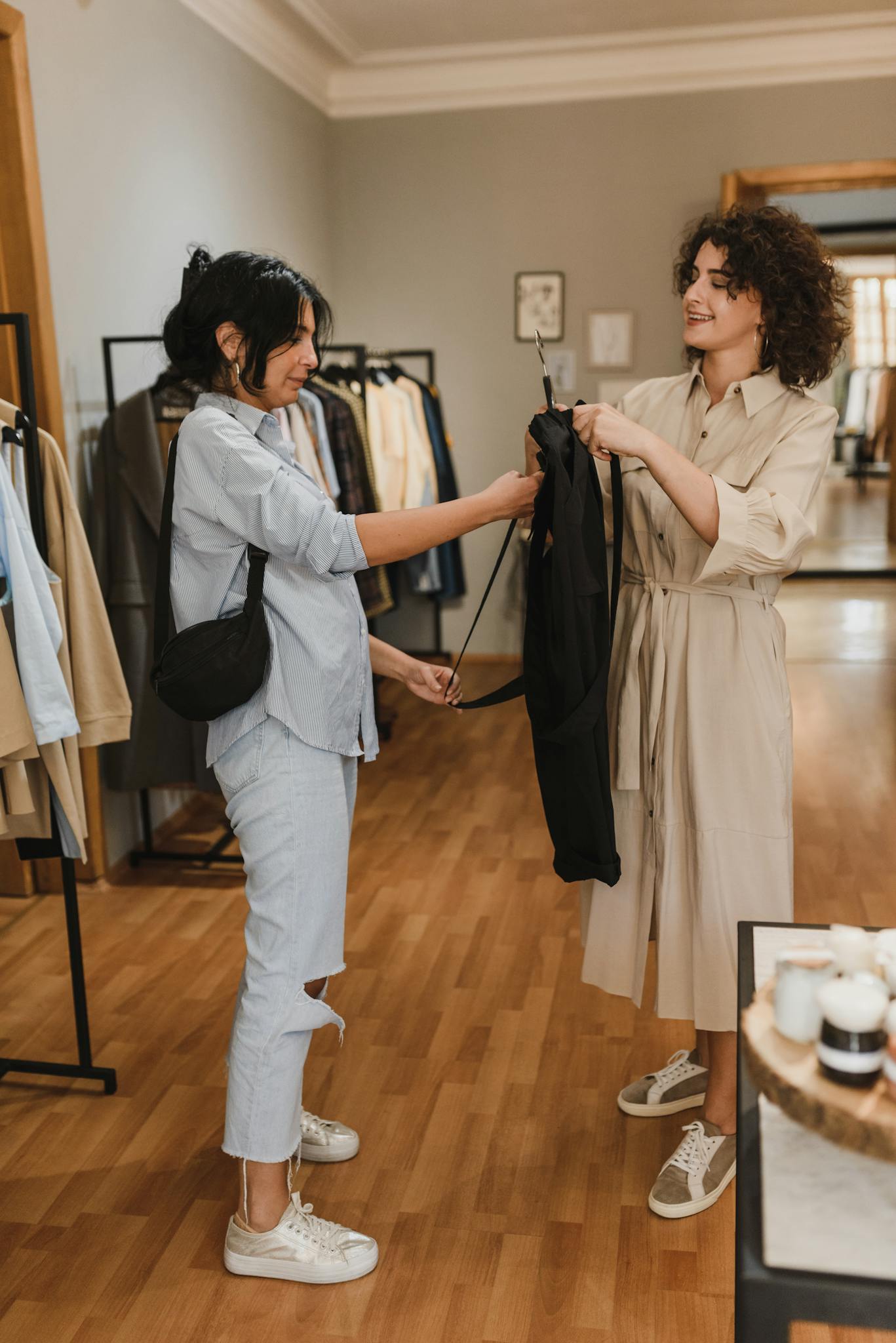 Women enjoying a shopping experience in a boutique, trying on clothes and smiling.