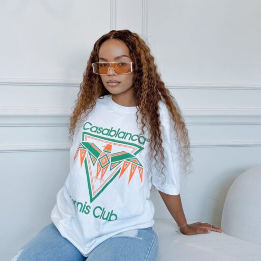Stylish woman in graphic Casablanca tee with trendy sunglasses indoors.